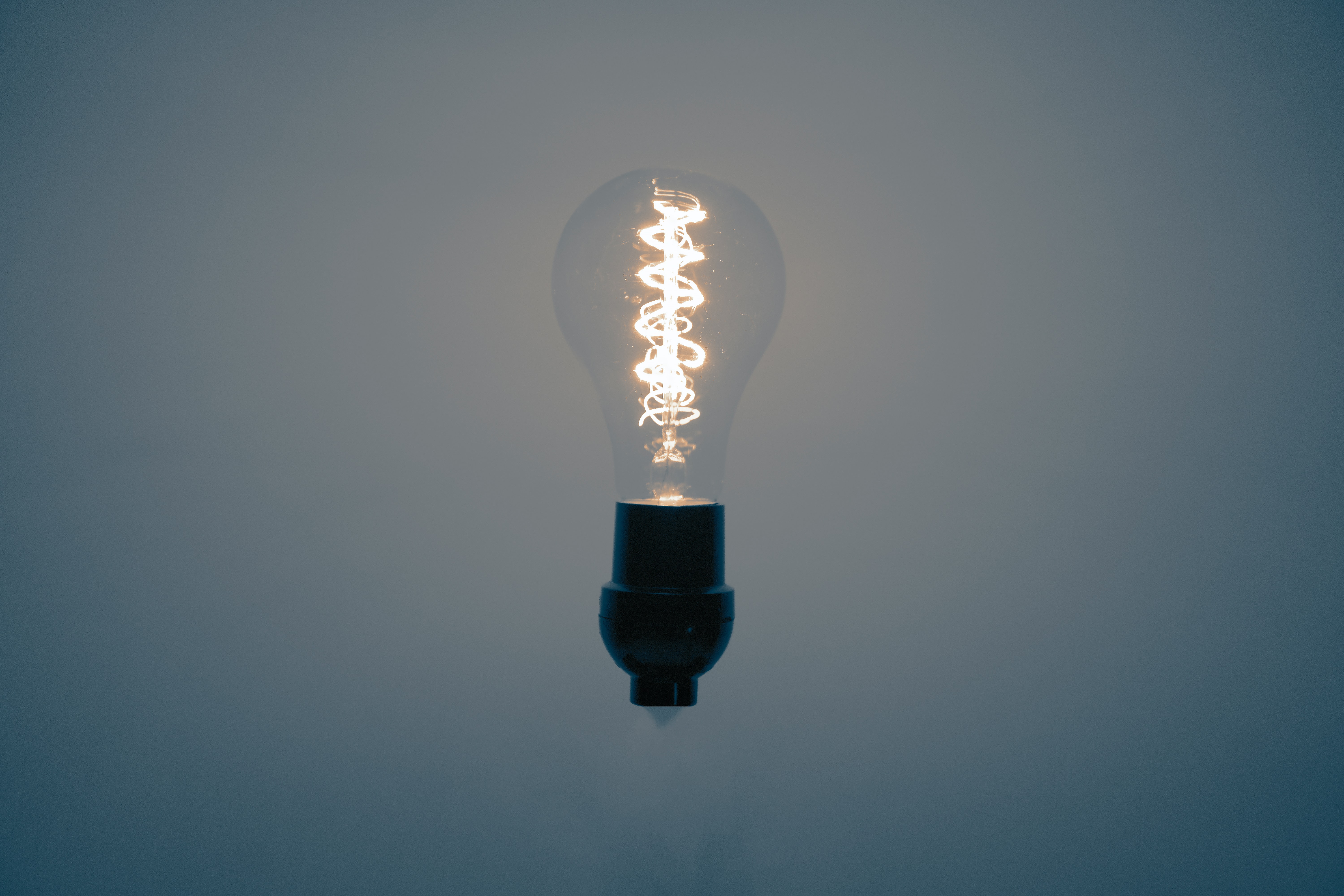 Lightbulb on a white background with a blue background. The lightbulb has a yellow light coming out of it.